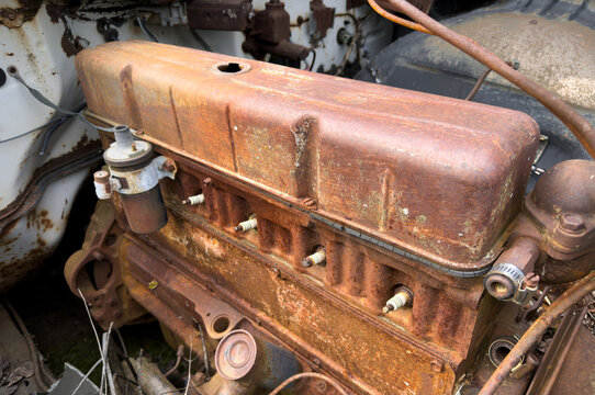 Detailed look at an old rusty car engine with four spark plugs
