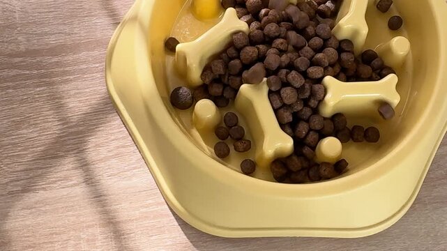 Pouring dry kibble into a yellow slow feeder dog bowl