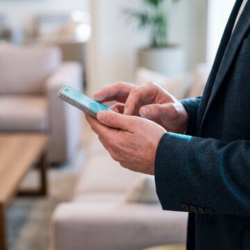 Close-up of a businessman using a modern smartphone in a bright office lounge or modern home interior