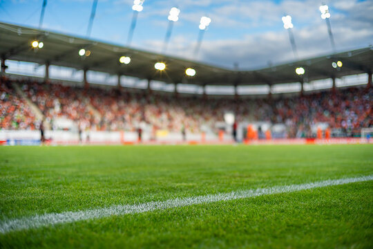 Professional soccer field with green grass and blurred stadium crowd under bright floodlights, creating a dynamic background for football and sports concepts.