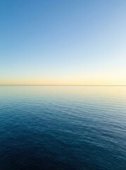 Obraz premium Tranquil Ocean View with Calm Blue Water and Clear Sky at Golden Hour Sunrise