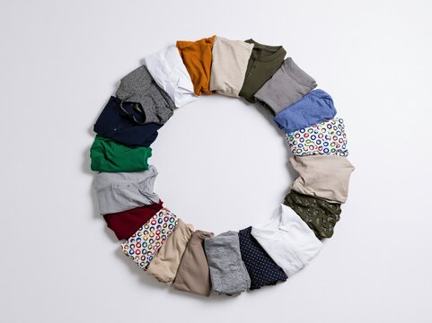 A circular arrangement of neatly folded t-shirts in various colors and patterns, forming a visually appealing and organized display, suggestive of a wardrobe or retail collection.