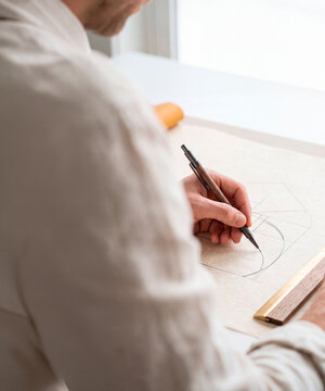 Architect or designer sketching geometric golden ratio diagram with mechanical pencil on drafting paper at desk