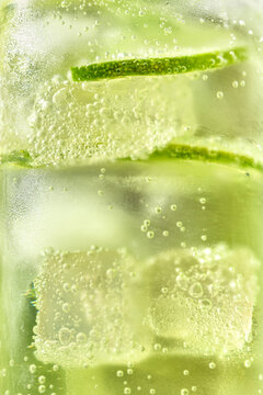A tall cocktail with lime slices and ice with bubbles