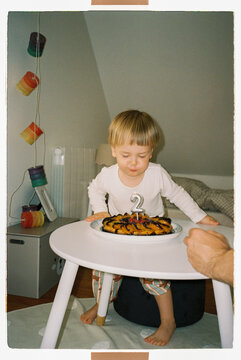 Two year old kid boy blowing out birthday candle on a second birthday