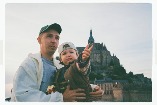 Father holding toddler in front of Mont Saint-Michel