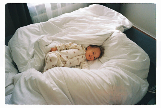 Toddler lying in a large white bed
