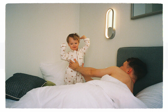 Father playing bonding with toddler on a bed at home