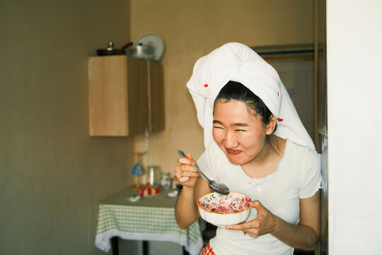 Young laughing asian woman standing indoors with a bowl of salad 