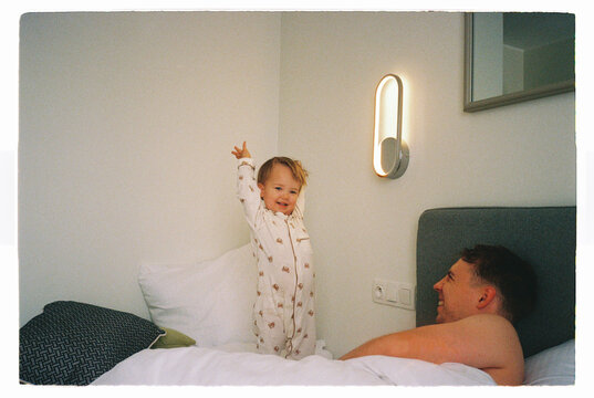 Playful toddler having fun on a bed with father