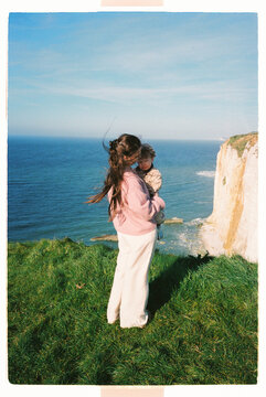 Mother holding child on a windy coastal cliff