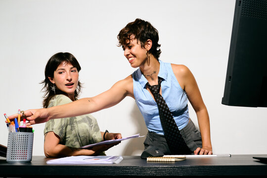 Two women collaborating at a desk. One points to a document while the other listens attentively. 