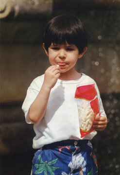 Young boy eating snack from bag outdoors