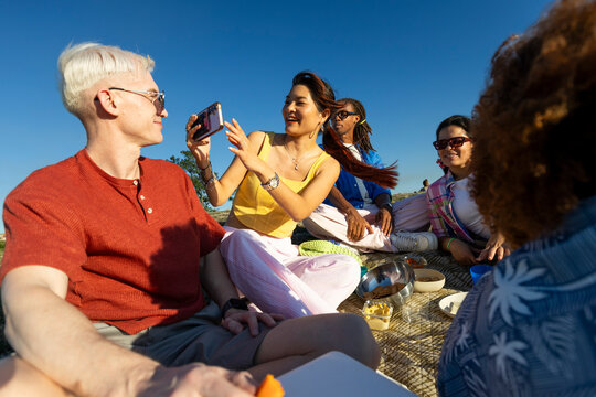 Friends having picnic and using smartphone