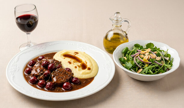 Veal stew in cherry sauce, served with mashed potatoes, green salad, and a glass of red wine