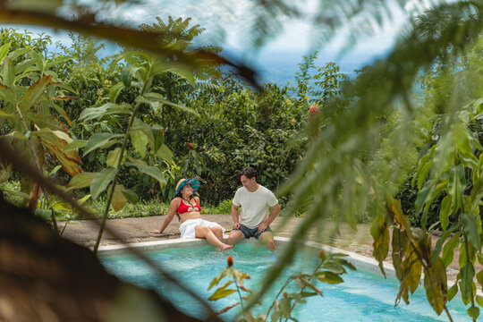 Couple relaxing by swimming pool in tropical resort