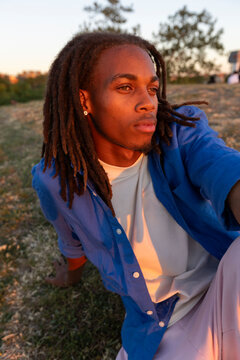 man with dreadlocks in sunlight sitting on the grass