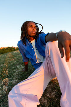 man with dreadlocks in sunlight sitting on the grass