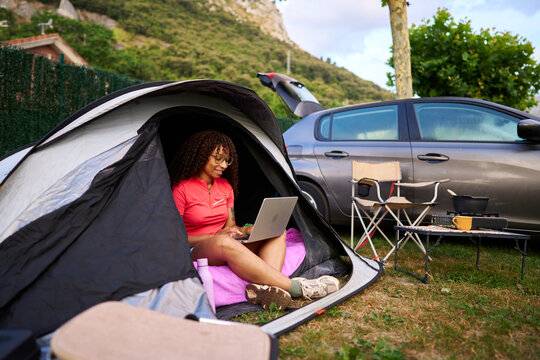 Woman working remotely at campsite using laptop