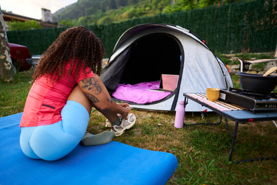 Woman resting at campsite using laptop tent outdoors