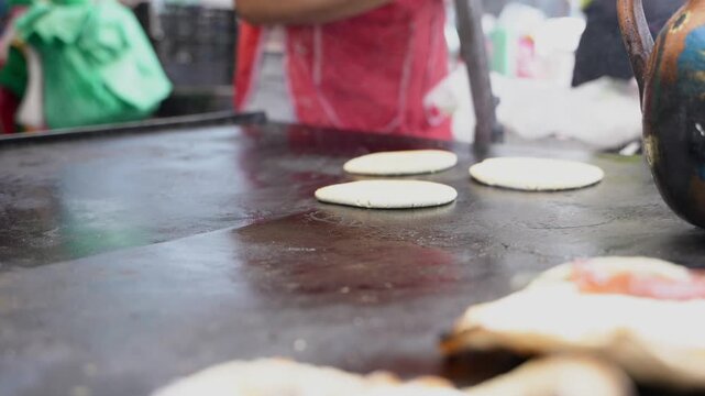 Mexican street food vendor cooking tortillas on a comal