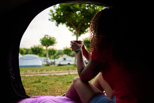 Woman enjoying morning coffee at campsite entrance