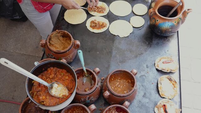 Mexican food vendor preparing sopes with stewed fillings on a comal