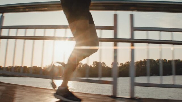 Male runner with prosthetic blade strides through sunset light