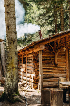 Rustic log cabin with chimney smoke in mountain forest