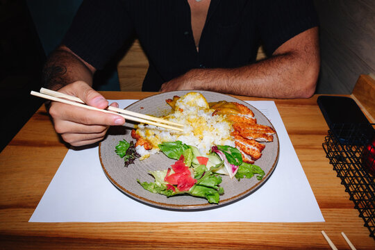 Person eating Japanese katsu curry with chopsticks