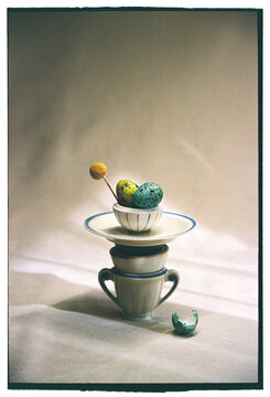 Colorful eggs stacked on teacups in a simple setup 