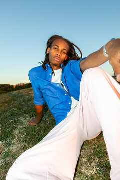 man with dreadlocks looking at camera sitting on the grass