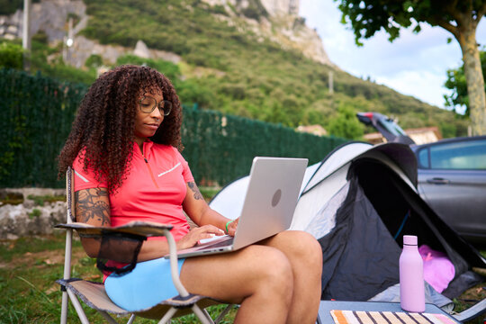 Woman working remotely at campsite using laptop