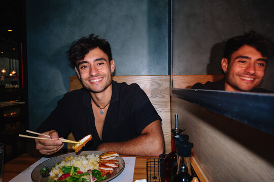 Smiling man eating Japanese katsu dish in restaurant