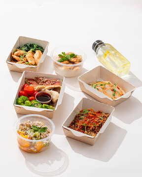 Assorted diet fitness food containers with fish chicken buckwheat dessert and lemonade on white background