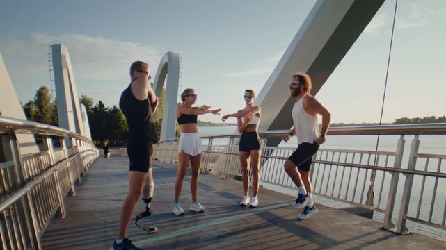 Runners perform warmup exercises with amputee athlete on bridge