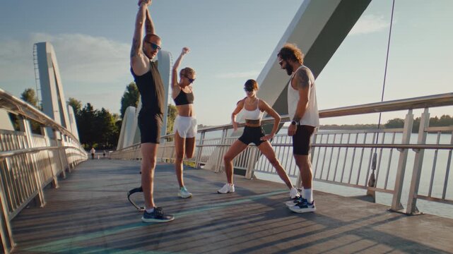 Fitness group warms up on bridge with adaptive male runner