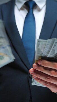 Formally dressed man is counting US Dollar bills, close-up.