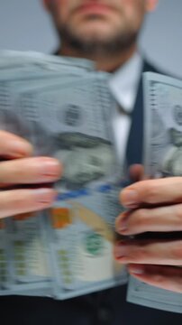 Formally dressed man is counting US Dollar bills, close-up.