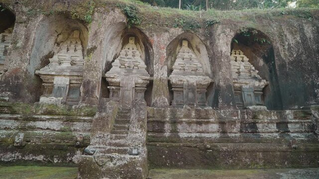 Ancient stone shrines and rock carvings at Gunung Kawi Temple surrounded by lush tropical vegetation in Tampaksiring Bali Indonesia