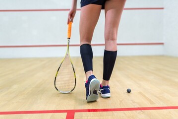 Fototapeta premium Legs of a female squash player with racket and ball