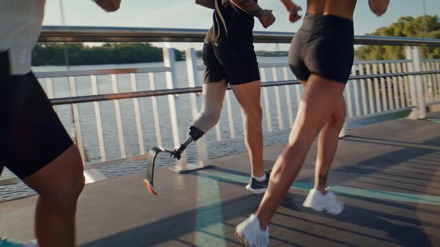 Group of runners jogs together against river during sunset