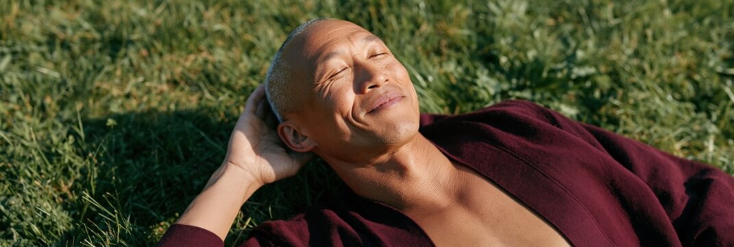 Relaxed man reclining on grass in nature for wellness background and outdoor lifestyle banner showcasing calm and sunlit leisure