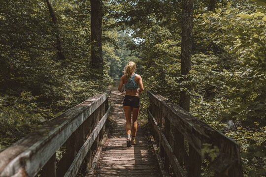 female trail runner crossing wooden bridge