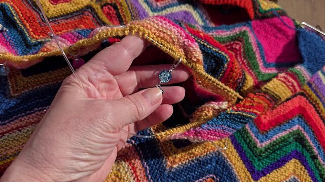 Decorative blue stitch marker on colorful wool knitting. Norway, Alver. August
