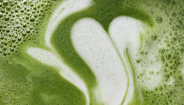 Close up view of creamy matcha green tea latte with artistic foam pattern.