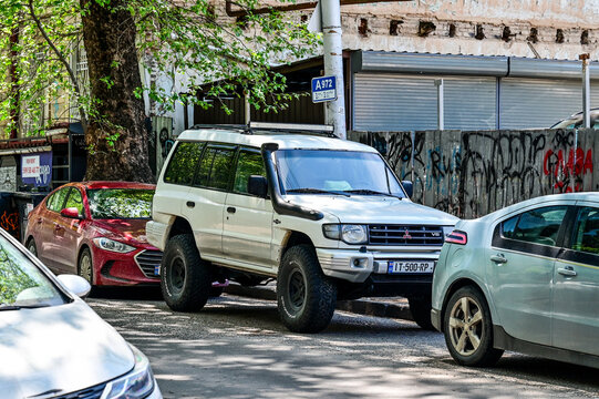 A white Mitsubishi Pajero V20 off-road vehicle from the 1980s and 1990s parked on the side of the road in Tbilisi; a modified off-road SUV Georgian license plates in the city, Tbilisi, Georgia 9.4.25