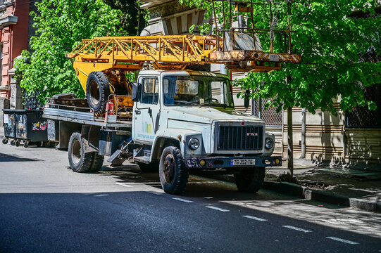 An old GAZ-3307 truck from the 1980s and 1990s with a boom lift parked on the side of the road in Tbilisi; a historic Soviet truck used as a municipal maintenance vehicle, Tbilisi, Georgia 9.4.25