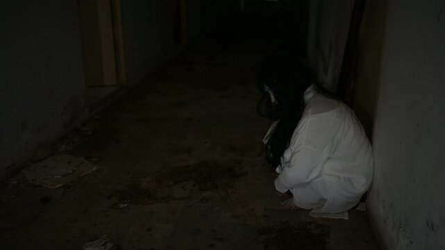 Dark horror scene of a mysterious figure in a white dress sitting alone in a dim abandoned room. Eerie shadows create a supernatural atmosphere for haunted house, paranormal and Halloween concepts.