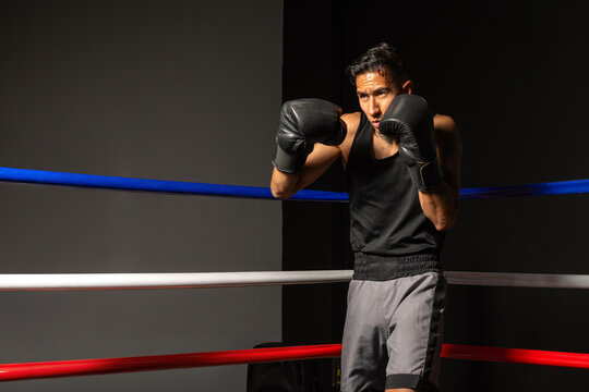 Young Hispanic boxer ready to begin training in boxing ring corner